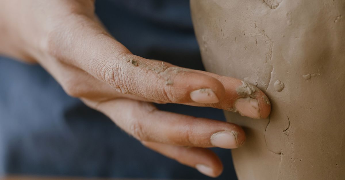 Hands shaping clay on a pottery wheel, close-up view of the forming process
